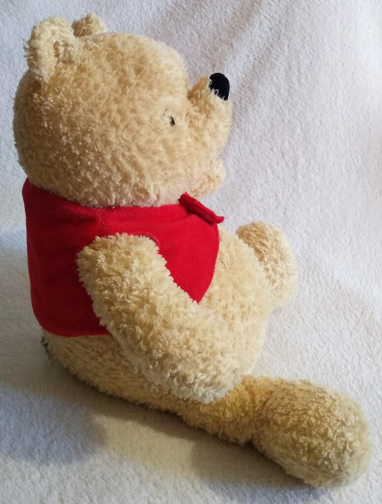 A side view of Winnie the Pooh, Classic Pooh plush by Golden Bear