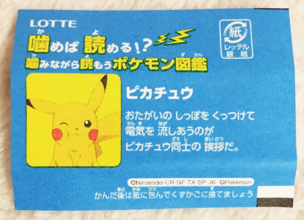 Xylitol Pokemon Chewing Gum Soda Flavour by Lotte - A blue wrapper with an image of a winking Pikachu on it with the text in Japanese "Pikachu greet each other by touching their tails and sending electricity through each other."